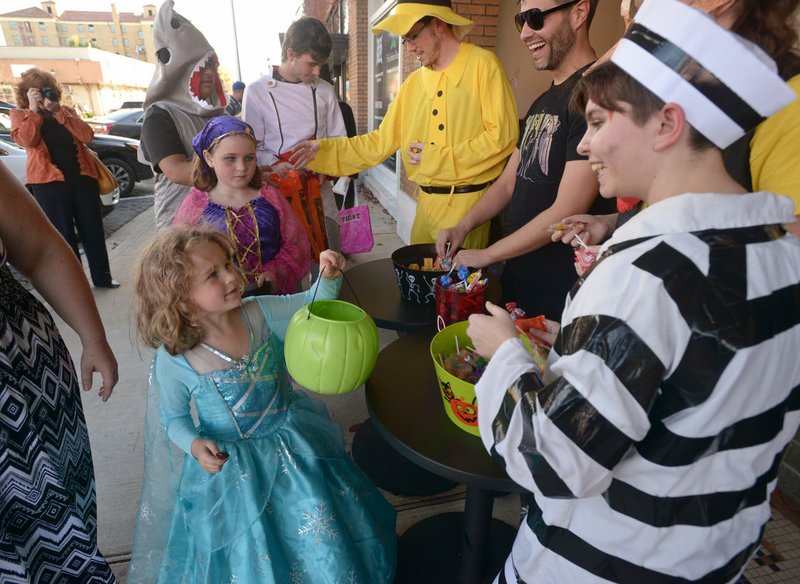 File Photo/BEN GOFF Virginia Graves and sister Jenny Graves of Bentonville get candy from Emerson Johnson, right, with Arkansas Public Theatre during last year's Main Street Rogers Goblin Parade in downtown Rogers. This year's trick-or-treat event is set for 3:30 to 5:30 p.m. Oct. 31 beginning at Frisco Park.