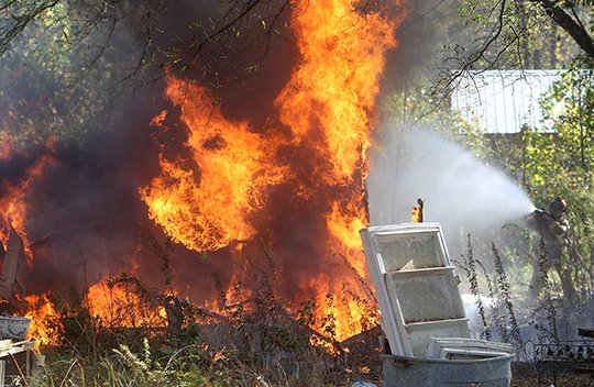 The Sentinel-Record/Richard Rasmussen STRUCTURE FIRE: A 70 West Fire Department firefighter sprays water on a structure that was destroyed by fire on South Harris Road Thursday morning.