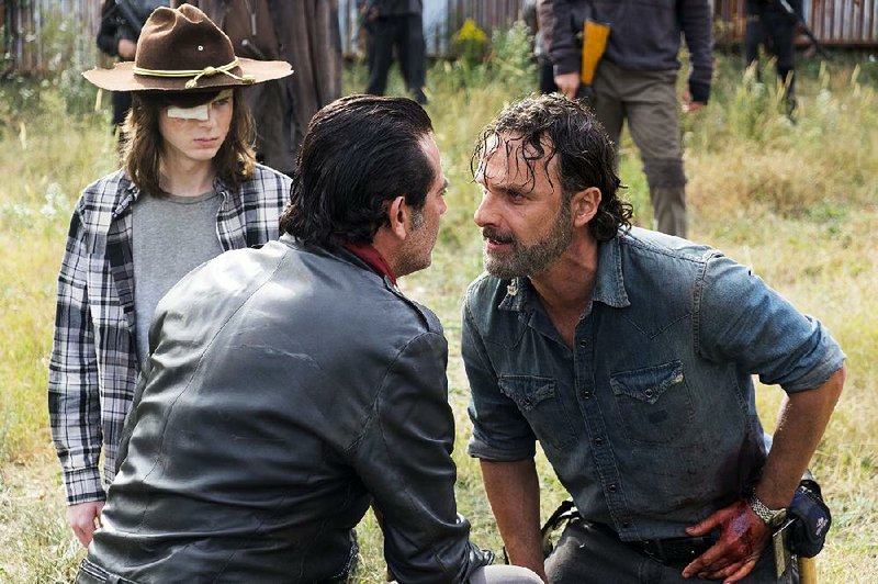 In a tense scene from last season’s fi nale, Rick (Andrew Lincoln, right) faces off against Negan (Jeffrey Dean Morgan) as Rick’s son, Carl (Chandler Riggs), looks on. The Walking Dead returns today to AMC.