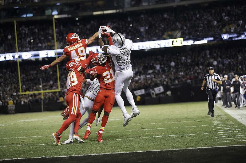 Oakland Raiders tight end Jared Cook (87) catches a pass over Kansas City Chiefs’ defenders to set up the Raiders’ game-winning touchdown on the last play of the game. The Chiefs gave up 505 yards in a 31-30 loss to the Raiders on Thursday night.