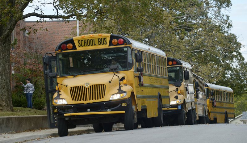 A row of buses wait Friday in front of Washington Elementary School in Fayetteville as students board buses for home after the school day.