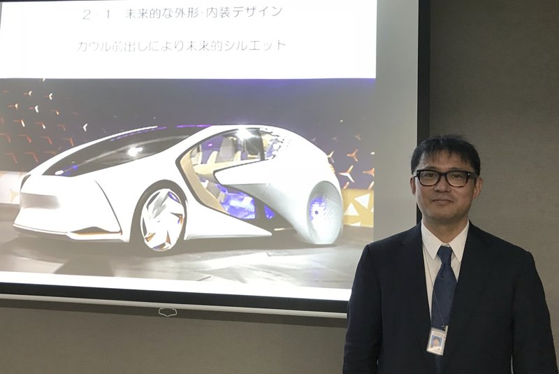 Toyota Motor Corp. manager Makoto Okabe stands in front of a image of the concept car &quot;TOYOTA Concept-i&quot; series Monday Oct. 16, 2017 in Tokyo. The use of artificial intelligence means cars may get to know drivers as human beings by analyzing their facial expressions, driving habits and social media use. (AP Photo/Yuri Kageyama)