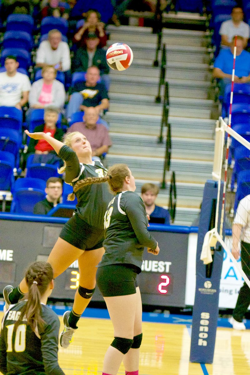 Photo courtesy of JBU Sports Information John Brown sophomore hitter Carly McKinney flys high in the air for a kill as sophomore middle Lindsey Davis, left, and senior hitter Karis Buff, right, back up the play against Bacone (Okla.) on Wednesday night at Bill George Arena. JBU won its fifth straight match to take a 3-0 sweep of the Warriors.