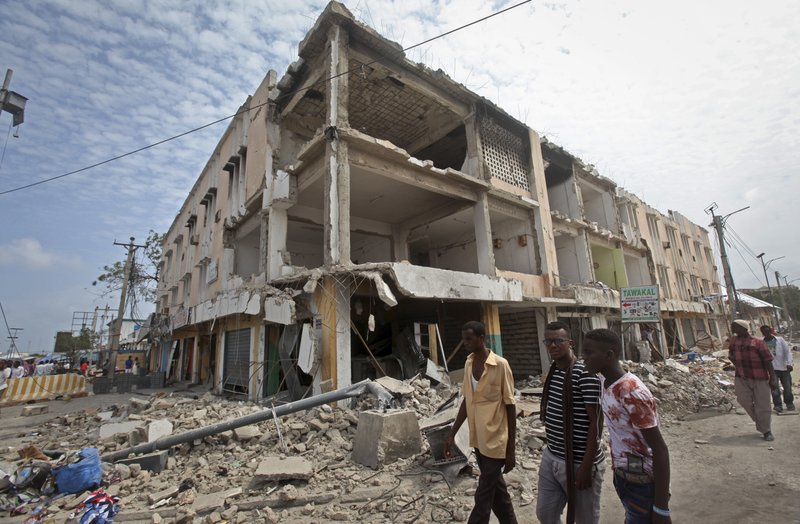 Men walk near destroyed buildings as thousands of Somalis gathered to pray at the site of the country's deadliest attack and to mourn the hundreds of victims, at the site of the attack in Mogadishu, Somalia Friday, Oct. 20, 2017. More than 300 people were killed and nearly 400 wounded in Saturday's truck bombing, with scores missing. 