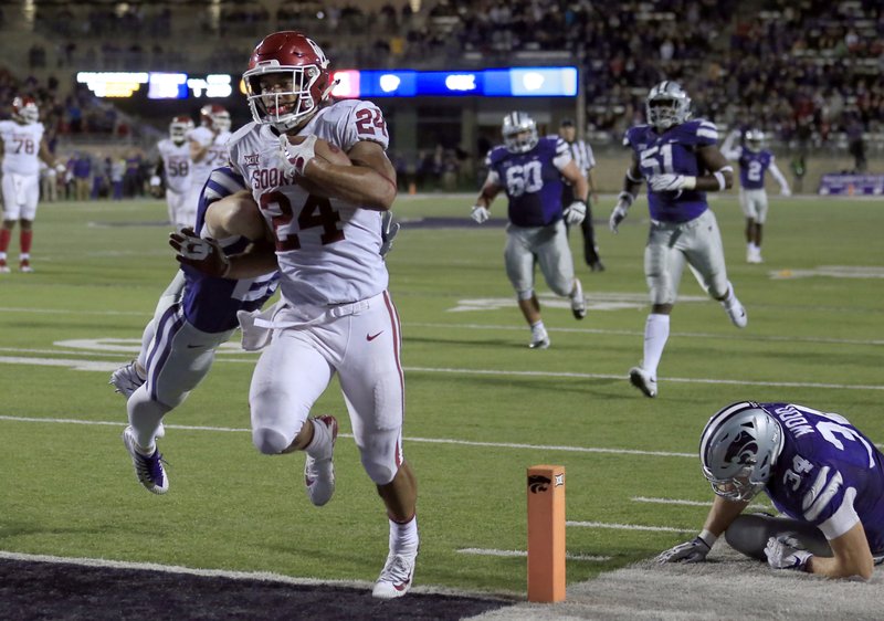 Oklahoma running back Rodney Anderson (24) scores a touchdown past Kansas State defensive back Sean Newlan (29) and Kansas State defensive end Tanner Wood (34) during the second half of an NCAA college football game in Manhattan, Kan., Saturday, Oct. 21, 2017. Oklahoma defeated Kansas State 42-35. (AP Photo/Orlin Wagner)
