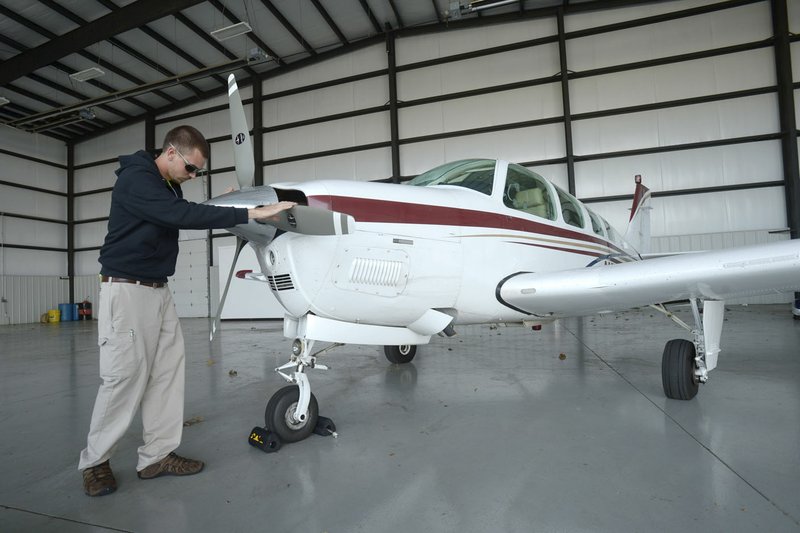 Ethan Kimes, a flight line operations technician, repositions the propeller Thursday before pulling a Beech Bonanza A36 out of a hangar and to the flight line for its owner at Drake Field in Fayetteville.