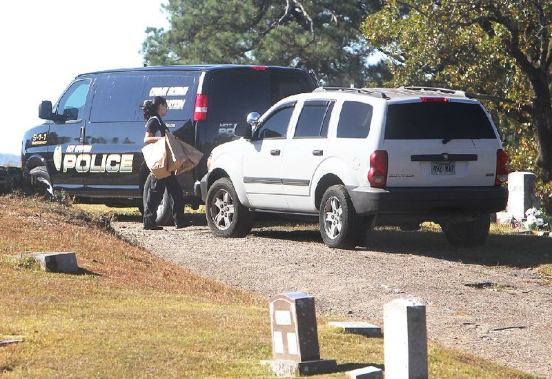 Hot Springs Police Department employee Jennifer Brizo loads evidence Monday into the crime scene van at Greenwood Cemetery in Hot Springs where the discovery of a body has prompted a homicide investigation.