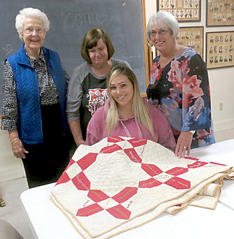 Lou Romine, Lavon Stark and Janice Waters, three members of the PieceMakers Quilt Club, pose with Randi Van Noy, (seated), curator of the Gravette Historical Museum, and an antique friendship quilt, which is part of the museum’s collections.