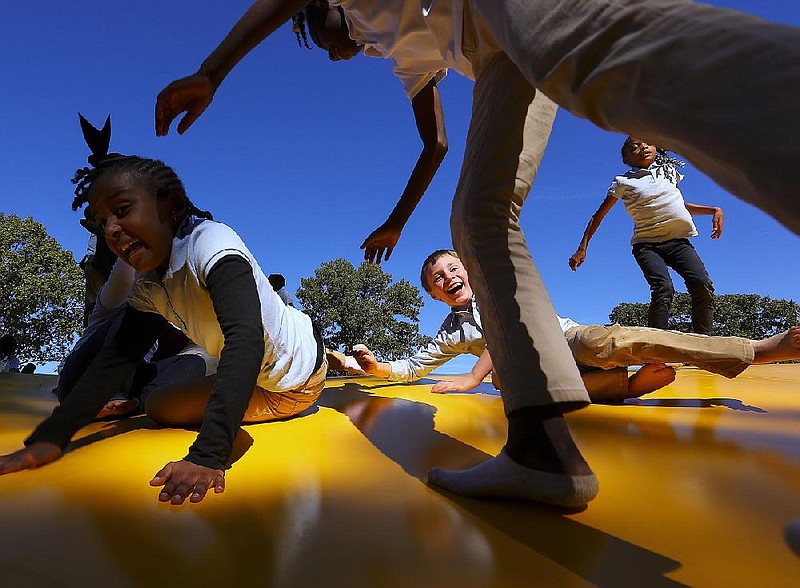 Second-graders from L.L.Owen Elementary School in Pine Bluff, Ni'Arry Quarles, left, Landon Inman, center, Ah'Rianna Neal, right, and Deyonna Williams, top, jump on a large inflated rubber pillow called a Kangaroo during a field trip to Motley's Pumpkin Patch in Little Rock in 2017.