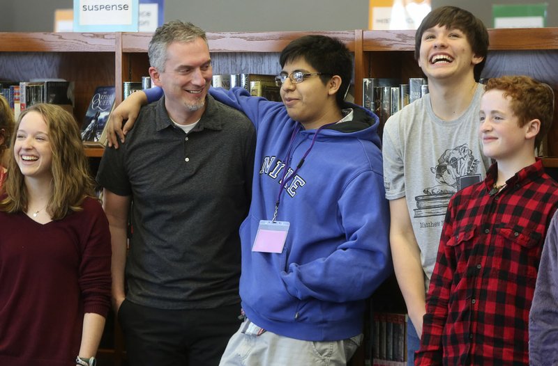 NWA Democrat-Gazette/DAVID GOTTSCHALK Jon Gil, a junior at the Fayetteville High School, places his arm around author James Dashner on Wednesday as they stand with library aids in the library at the high school. Dashner spoke to the freshman class and a creative writing class at the school as part of the True Lit: Fayetteville Literary Festival.