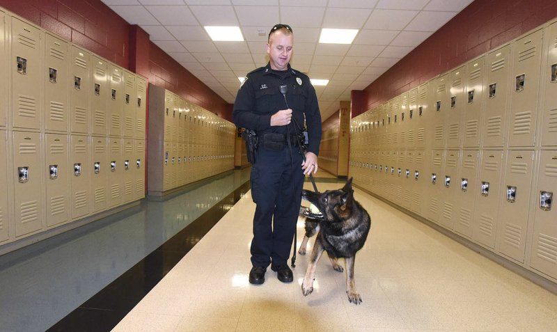 NWA Democrat-Gazette/FLIP PUTTHOFF Andy Ball with the Bentonville Police Department walks a hall Wednesday at Bentonville High School with Tyson, an 8-year-old male police dog. The School District, in collaboration with the Bentonville and Centerton police departments, is implementing random patrols using police dogs at its two high schools and three junior high schools.