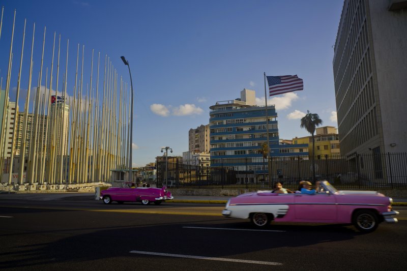 FILE - In this Jan. 12, 2017 file photo, tourists ride in classic American convertible cars past the United States embassy, right, in Havana, Cuba. Cuba on Oct. 26 presented its most detailed defense to date against U.S. accusations that American diplomats in Havana were subjected to mysterious sonic attacks that left them with a variety of ailments including headaches, hearing problems and concussions. (AP Photo/Ramon Espinosa, File)