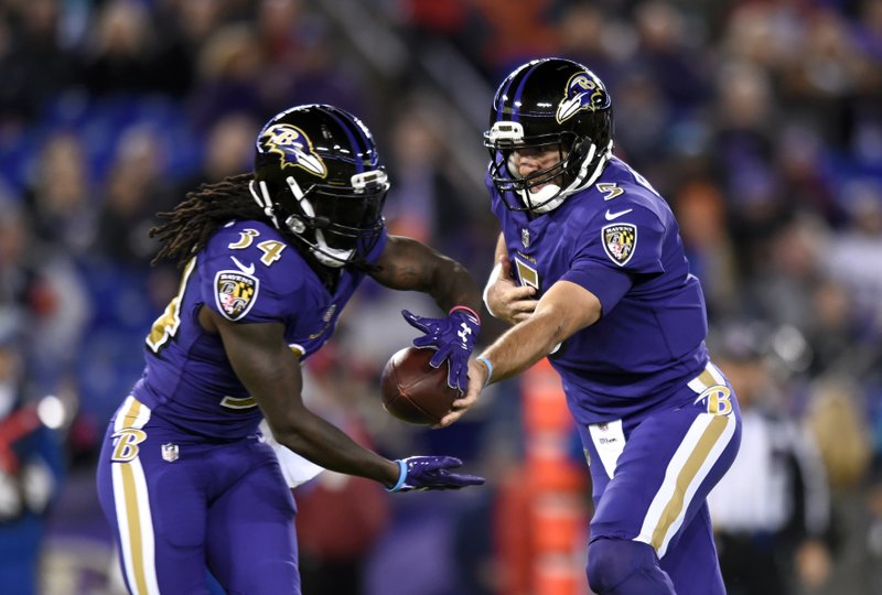 Baltimore Ravens quarterback Joe Flacco, right, hands off to Baltimore Ravens running back Alex Collins in the first half of an NFL football game against the Miami Dolphins, Thursday, Oct. 26, 2017, in Baltimore. (AP Photo/Gail Burton)

