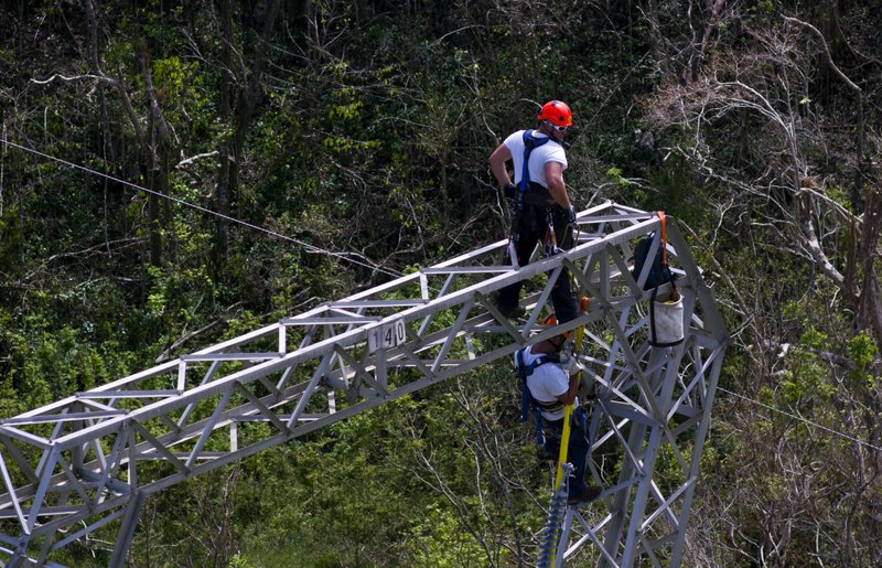In this Oct. 15, 2017, file photo, Whitefish Energy Holdings workers restore power lines damaged by Hurricane Maria in Barceloneta, Puerto Rico. 