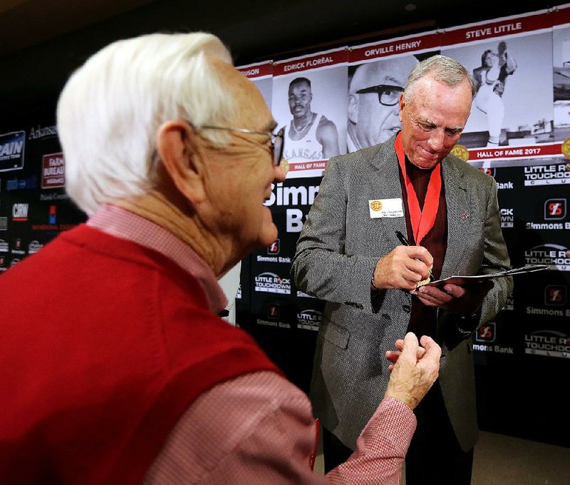 Former Razorback Joe Ferguson (right) signs an autograph for Tommy Fisher of Maumelle after the Southwest Conference Hall of Fame ceremony during the Little Rock Touchdown Club meeting Monday at the Embassy Suites in Little Rock.