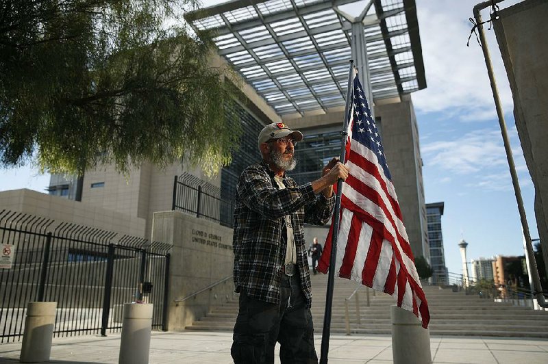 David Fleeman, a supporter of Cliven Bundy and his co-defendants, holds a flag outside the federal courthouse in Las Vegas on Monday. Juror selection began in the trial stemming from an armed standoff with federal agents in 2014.