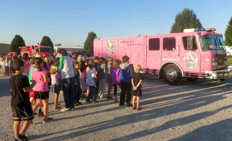 Photo by Susan Holland Students, teachers and staff poured out onto the parking lot at Gravette Upper Elementary School early on Monday morning, Oct. 9, to greet Pink Heals tour members. The youngsters were fascinated by the big pink fire truck, pink ambulance and police car and were excited to be able to help honor their schoolmates, Brooklyn Carte and Sarah Hollingworth, fifth graders who are battling cancer.