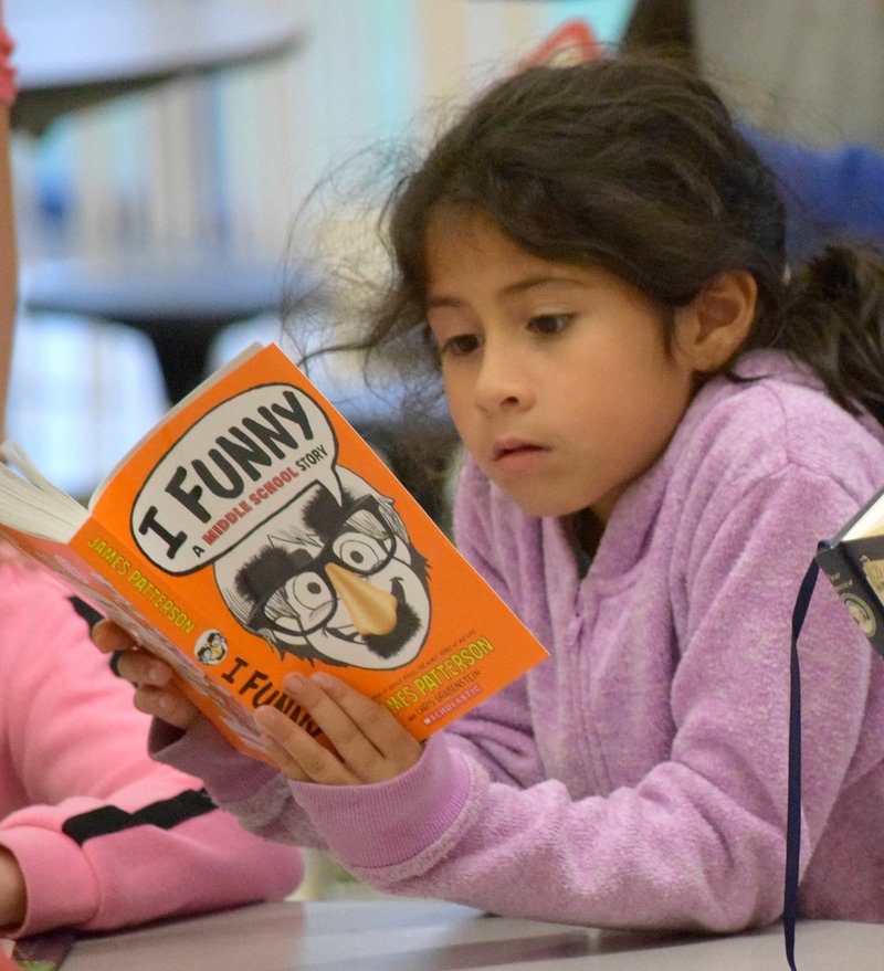 Photo by Mike Eckels Tiffany Martinez, a third-grader at Decatur Northside Elementary School, gets wrapped up in a book during the Decatur SPARK program's Eat and Read event in the cafeteria of Northside Elementary Oct. 10.