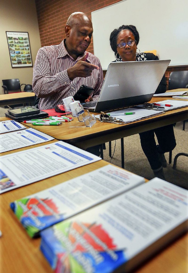 Cornelius Mabin and Rumel Driver, health insurance navigators, discuss provider information Wednesday at the Laman Library in North Little Rock while waiting to assist people in signing up for or renewing Patient Protection and Affordable Care Act coverage. The law’s fifth annual enrollment season began Wednesday, and navigators for the Arkansas Health Insurance Marketplace will set up at various locations throughout the 45-day sign-up period. 