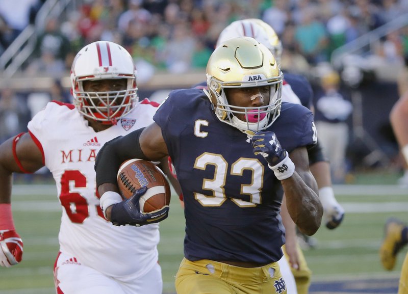 FILE - In this Sept. 30, 2017, file photo, Notre Dame running back Josh Adams (33) heads for the end zone for his second touchdown of the game during the first half of an NCAA college football game against Miami (Ohio) in South Bend, Ind. The noise about a playoff bid and the Heisman Trophy is getting louder around No. 5 Notre Dame as it prepares for the visit from Wake Forest on Saturday, Nov. 4. Junior running back Adams, fifth in the nation in rushing with 1,169 yards, has emerged as a legitimate contender for the Heisman and other postseason awards. (AP Photo/Charles Rex Arbogast, File)