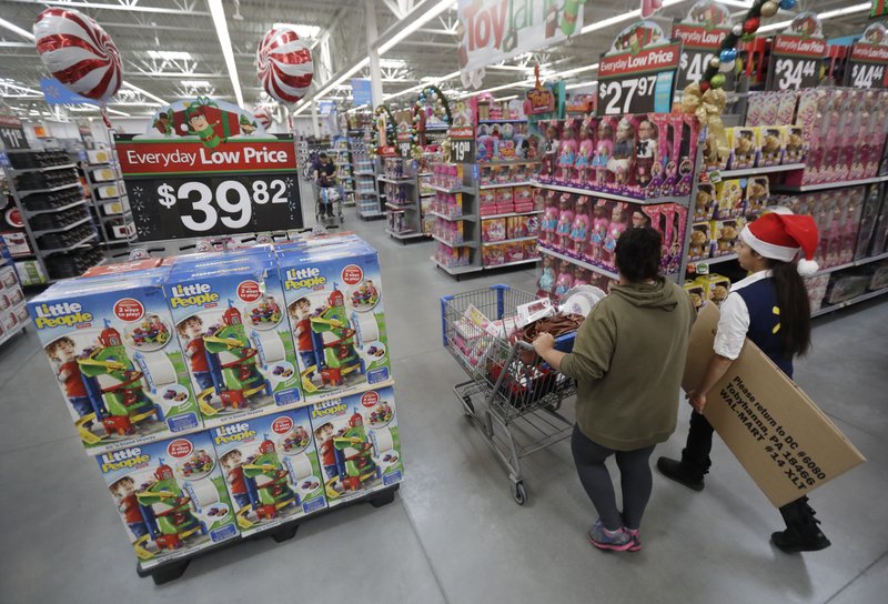 A shopper, left, walks with a store associate in October 2016 in the toy section at Walmart in Teterboro, N.J. As more shoppers shift online, Walmart hopes to make its stores more fun this holiday season. The chain will have parties for customers at its stores for the first time, increase the number of product demonstrations and expand the role of employees who last year helped people find the shortest register lines. Many retailers are trying to make stores more inviting even as they improve online services. (AP Photo/Julio Cortez, File)
