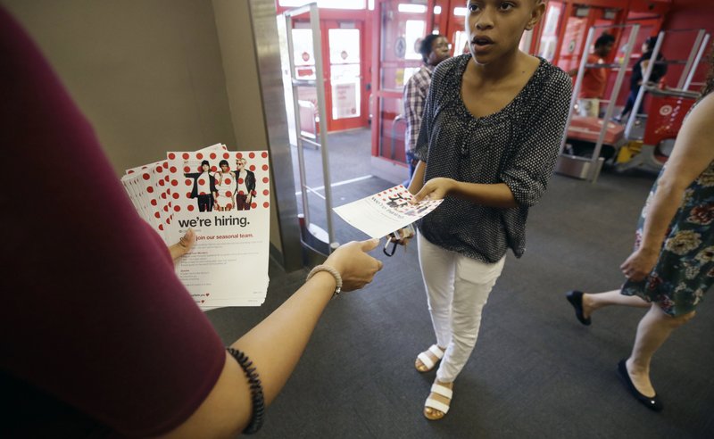 A potential job candidate takes a flyer from a human resources representative Oct. 13 at a Target store in Dallas. The U.S. government issued the October jobs report Friday. (AP Photo/LM Otero)
