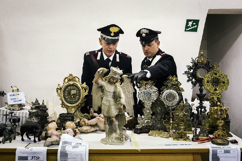 Members of Italy’s art theft police unit examine a stolen 16th-century statue of the archangel Michael and other religious artifacts they’ve recovered after months of investigations at their headquarters in Naples, Italy. The country’s 60,000 churches are a vast trove of artwork and artifacts, and protecting them from theft is a full-time task. 