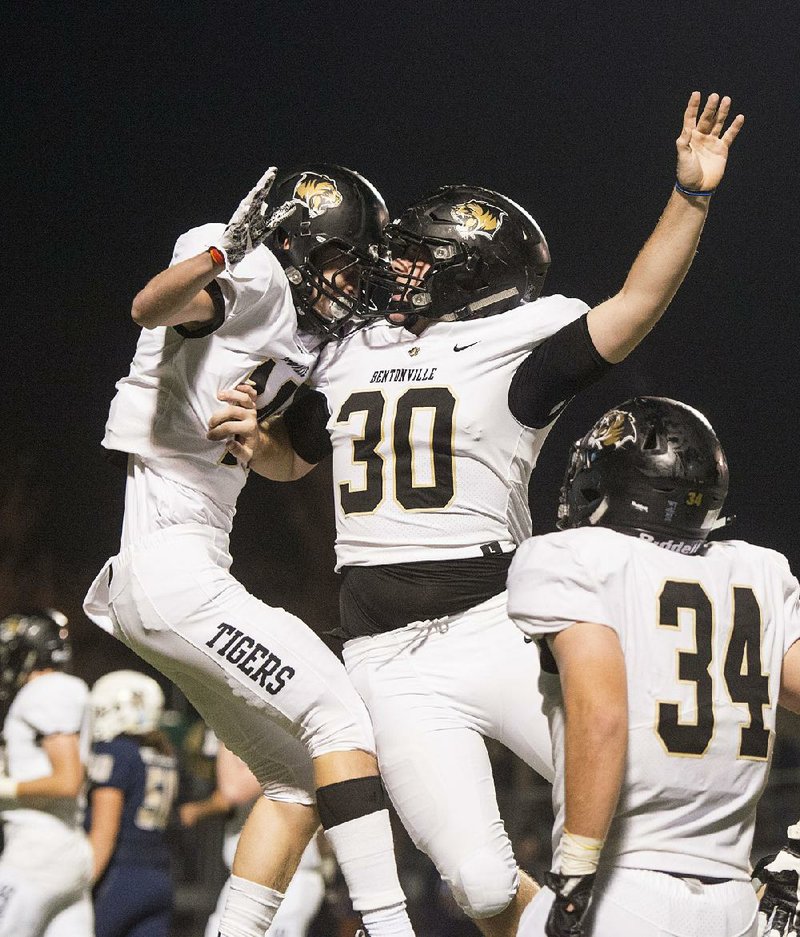 Bentonville’s Dylan Smith (left) celebrates  with  teammate Landon Beeler after scoring a touchdown Friday during  the Tigers’ 37-28 victory over Bentonville West at Tiger Stadium in Bentonville.