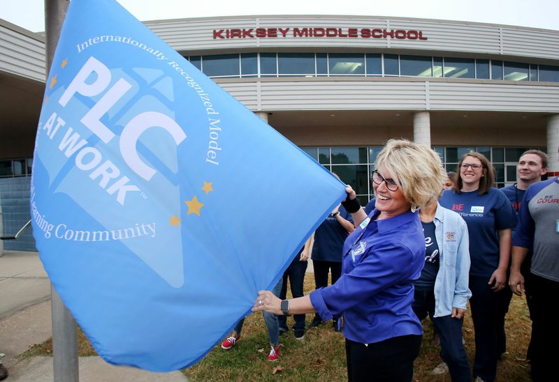 NWA Democrat-Gazette/DAVID GOTTSCHALK Mel Ahart, principal at Kirksey Middle School, stands with faculty and staff Friday as she guides a new flag recognizing the school as National Model Professional Learning Community at Work by Solution Tree at the Rogers school. The flag raising followed a surprise pep rally.