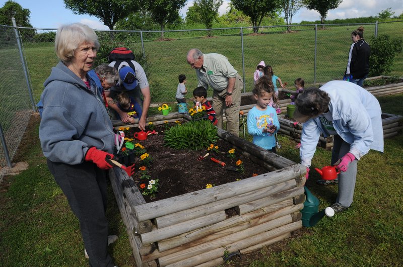 Greta Thiele (left) with Benton County Master Gardeners helps students at the Sunshine School and Development Center plant flowers in the therapy garden at school. "A Very Special Art Show" on Friday will benefit the school's preschool and community support services.