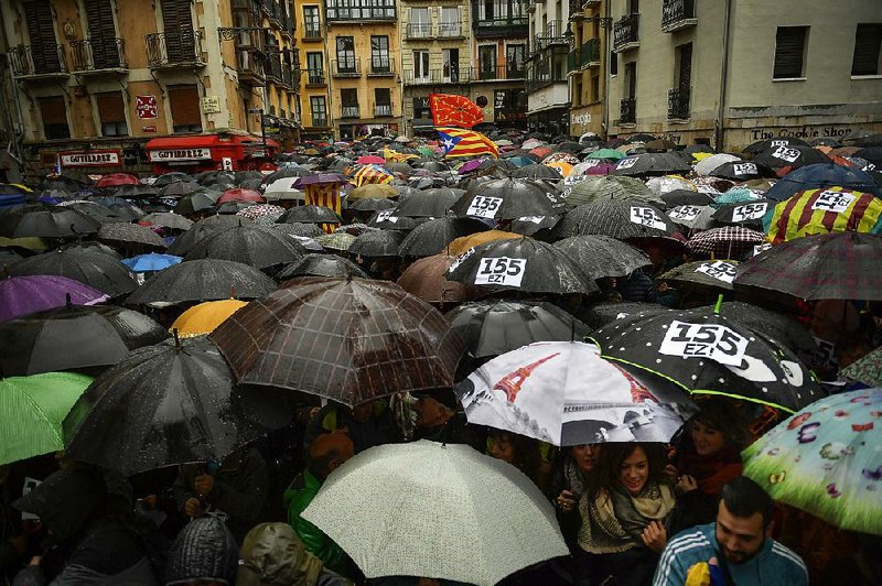 People take shelter Sunday under umbrellas at Pamplona’s Plaza Consistorial square during a protest against Article 155 of the Spanish constitution, which gives the central government extra powers to re-establish the rule of law in a region.
