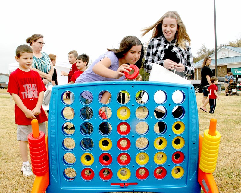 LYNN KUTTER ENTEPRISE-LEADER Caitlin Early, 10, left, competes against her older sister, Kristen Early, 11, in a life-size game of Connect Four. The sisters were at a Fall Festival, sponsored by Farmington Public Library on Saturday morning. Many families showed up on windy, warm fall day to enjoy games, crafts and other activities on the grassy vacant lot located next to the Library.