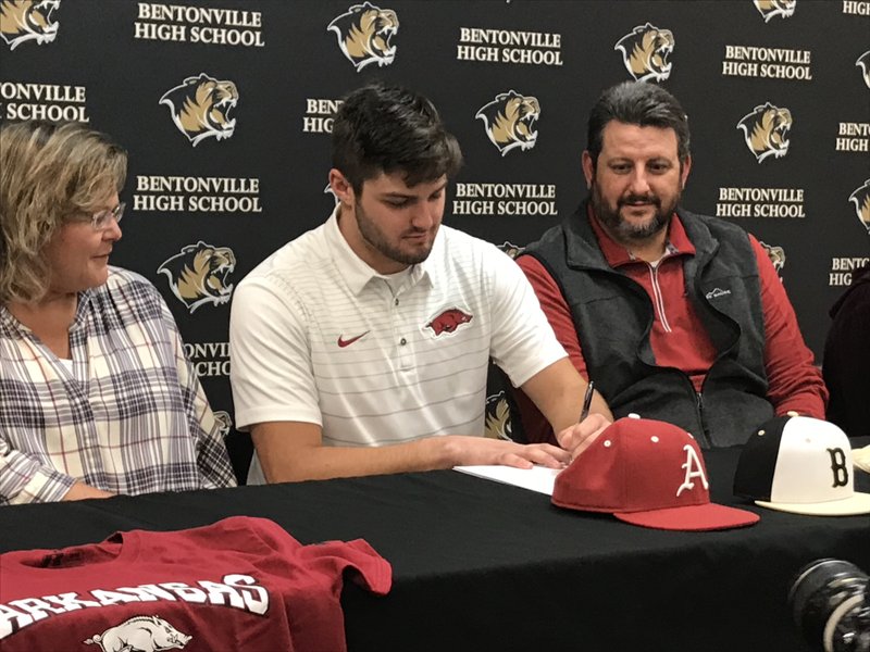 STAFF PHOTO / HENRY APPLE Bentonville first baseman Tyler Johnson (center) signs a national letter of intent to play baseball at Arkansas during Wednesday's ceremony at the Tiger Athletic Complex.