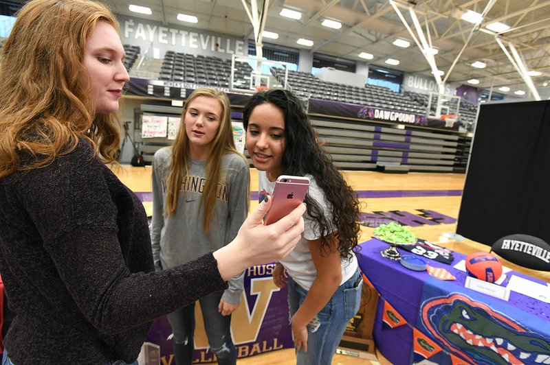 NWA Democrat-Gazette/J.T. WAMPLER Haley Warner (RIGHT) and Ella May Powell look at photographs with Emily Harris of Rogers (LEFT) Tuesday Nov. 8, 2017 at Fayetteville High School. Warner signed a letter of intent to play volleyball for the University of Florida and Powell with the University of Washington.
