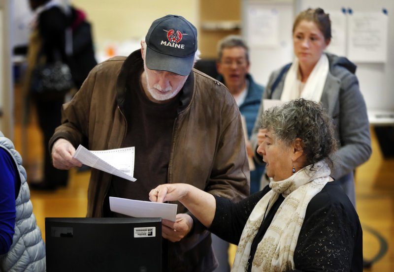 Michael Parent, left, gets instructions on submitting his ballots from warden Denise Shames while voting Tuesday, Nov. 7, 2017, in Portland, Maine. Voters in Maine will decide if they want to join 31 other states and expand Medicaid under former President Barack Obama's Affordable Care Act. It's the first time since the law took effect that the expansion question has been put before voters. (AP Photo/Robert F. Bukaty)