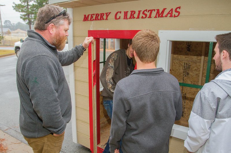 Jamie Jones, left, construction technology instructor at Benton High School, gives directions to students Justin Beard, in the doorway, from left, Connor Pinkerton and Carter Wood. The shop class built three vignettes, or small open houses, that will be displayed at the Saline County Courthouse in downtown Benton.