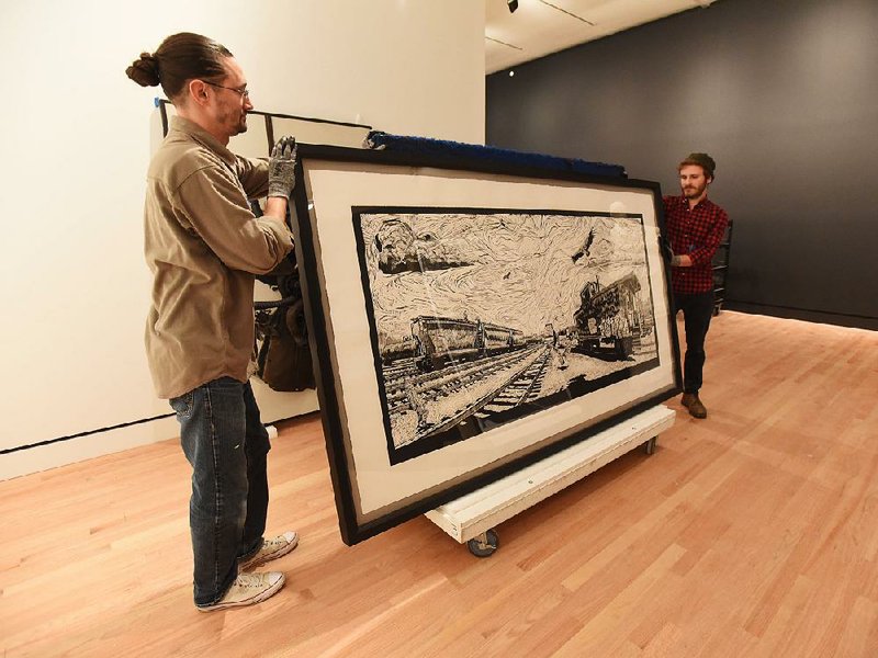 Drew Divilbiss (left) and Michael Derian move a piece of art Wednesday at Crystal Bridges Museum of American Art in Bentonville. Several works that have been on the road at other museums are now back at Crystal Bridges.