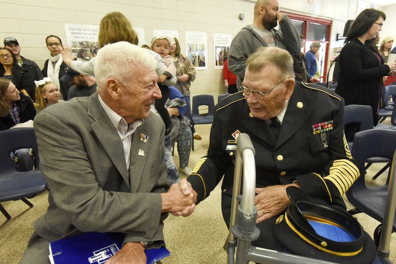 E.S. Lawbaugh of Fayetteville (left), Marine Corps veteran, and Army veteran Lucion Cowart of Rogers chat Friday at a Veterans Day performance by students at Westside Elementary School in Rogers. Lawbaugh was keynote speaker at the event. Students sang patriotic songs under the direction of music teacher Pamela Pittman and heard video remarks from veterans.