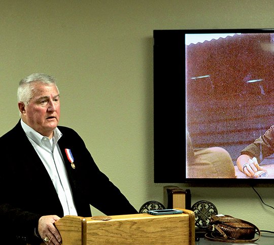 The Sentinel-Record/Richard Rasmussen SHARING HIS STORY: Retired U.S. Army Lt. Col. Hugh Mills, a Hot Springs native, speaks about his experiences during three tours of Vietnam next to a photo of himself during the war before showing a trailer of a new documentary in the works about his return trip to Vietnam during a recent presentation to the members of the John Percifull Chapter of the Daughters of the American Revolution.