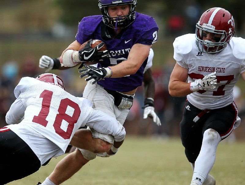 Ouachita Baptist’s Drew Harris (2) tries to shake off Henderson State defensive back Malcom Scott (18) during the third quarter of OBU’s 49-42 victory Saturday at Cliff Harris Stadium in Arkadelphia. Harris had 216 yards and scored 7 touchdowns.