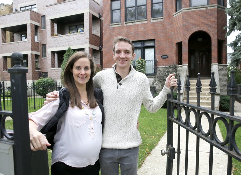 In this Sunday, Oct. 15, 2017, photo, Emily and Brian Townsend pose outside their home where they own the top floor unit in a three-flat building in Chicago. (AP Photo/Charles Rex Arbogast)