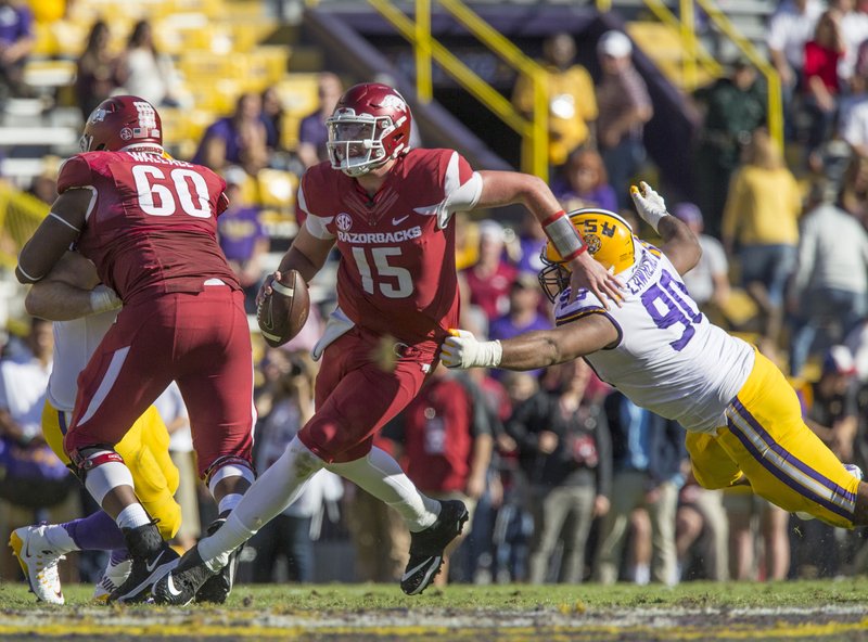 NWA Democrat-Gazette/Ben Goff NO ESCAPE: Redshirt freshman Arkansas quarterback Cole Kelley (15) evades LSU defensive end Rashard Lawrence in the fourth quarter Saturday at Tiger Stadium in Baton Rouge, La. Kelley, who was arrested Sunday morning on suspicion of driving while intoxicated and reckless driving, has been indefinitely suspended from the team by head coach Bret Bielema.