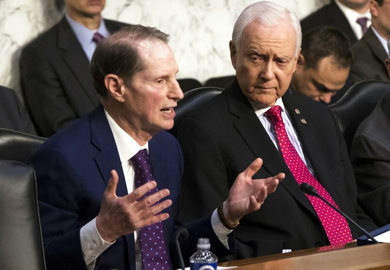 Sen. Ron Wyden, D-Ore., left, the top Democrat on the Senate Finance Committee, criticizes the Republican tax plan while Chairman Orrin Hatch, R-Utah, listens to his opening statement as the panel begins work overhauling the nation's tax code on Capitol Hill in Washington on Monday, Nov. 13, 2017. 