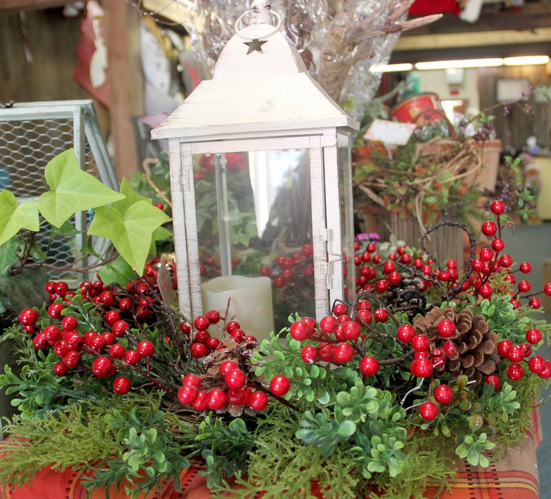 LYNN KUTTER ENTERPRISE-LEADER A lantern surrounded by greenery and hollyberries can make a simple table centerpiece or place on a coffee table.