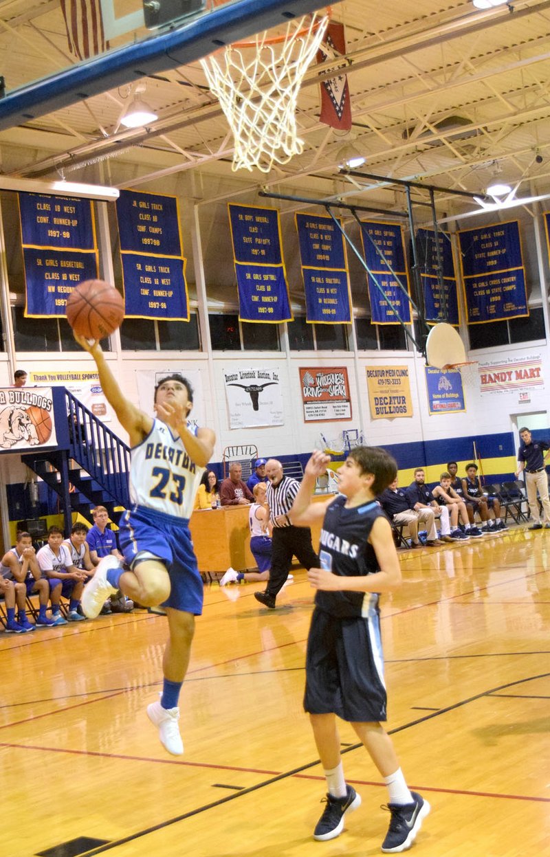 Photo by Mike Eckels Andres Revolorio (Decatur 23) went up for a layup while Ayden Merryman (New School 2) waited for the possible rebound during the Bulldog-Cougar junior-high basketball game at Peterson Gym in Decatur Nov. 6. The Fayetteville New School won the contest, 41-28.