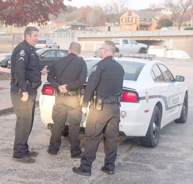 Keith Bryant/The Weekly Vista K-9 handler Travis Trammell (left) explains some of the idiosyncrasies of traffic stops while officer Blake Hughes poses as a cuffed suspect and officer Greg Haigh, who is in his second week of field training, listens and asks questions.