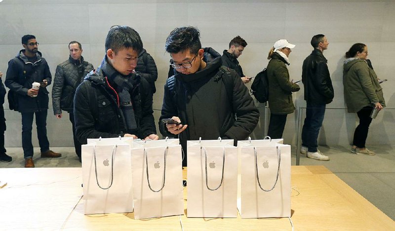 Two visitors from China configure an iPhone X they bought at an Apple store in Chicago. The U.S. Commerce Department released retail sales data for October on Wednesday. 