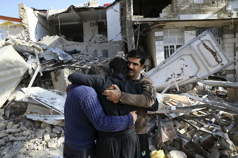 Earthquake survivors mourn Wednesday outside destroyed homes in Sarpol-e-Zahab in western Iran. 