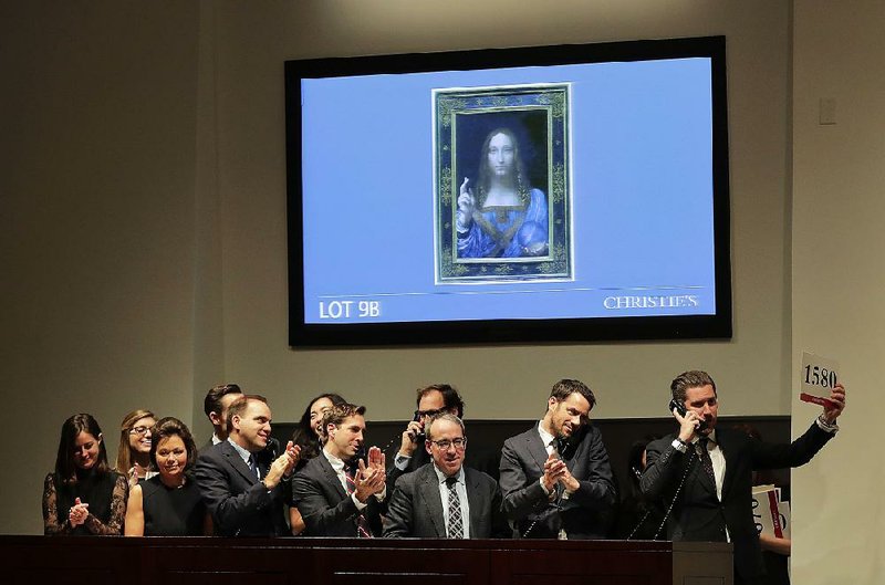 Bidding representatives stand under a video image of Leonardo da Vinci’s Salvator Mundi after it sold for $450 million at auction Wednesday evening at Christie’s in New York. 

