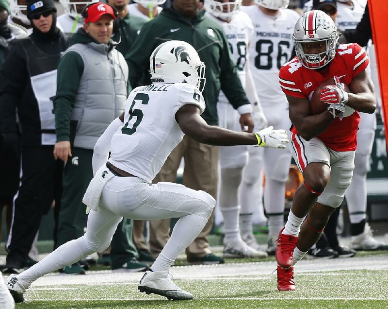 Ohio State receiver K.J. Hill, right, runs after a catch as Michigan State safety David Dowell defends during the first half of an NCAA college football game Saturday  in Columbus, Ohio.  Hill caught 2 passes for 19 yards to help Ohio State win 48-3.